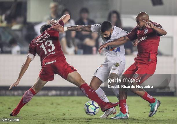 Gabriel of Santos battles for the ball with Patrick and Dourado of Internacional during a match between Santos and Internacional as a part of...