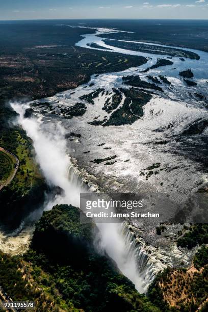 aerial view of the victoria falls pouring down with spray rising high since the waters of the zambezi river are in full flood, zimbabwe - james strachan stock pictures, royalty-free photos & images