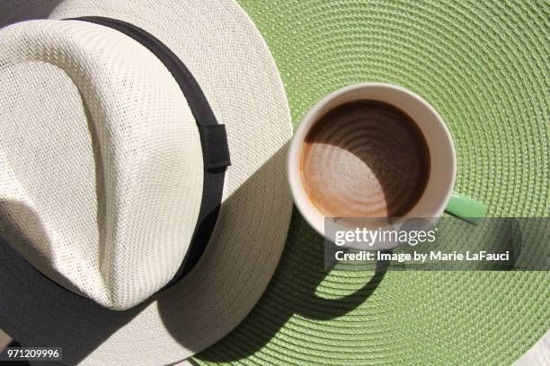 top view of coffee cup with straw hat on green placemat - marie lafauci stock pictures, royalty-free photos & images