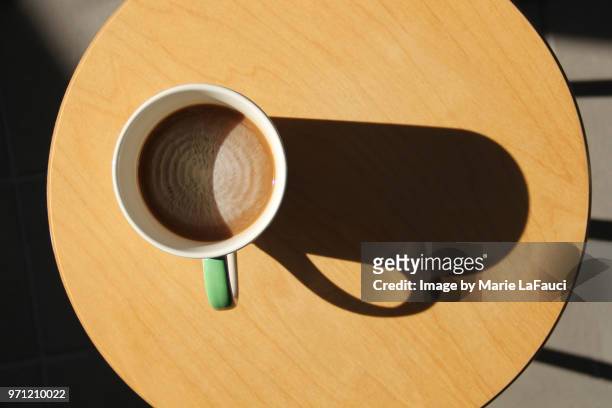 close-up of coffee mug on wood table with large shadow - chocolate swirl from above stock pictures, royalty-free photos & images