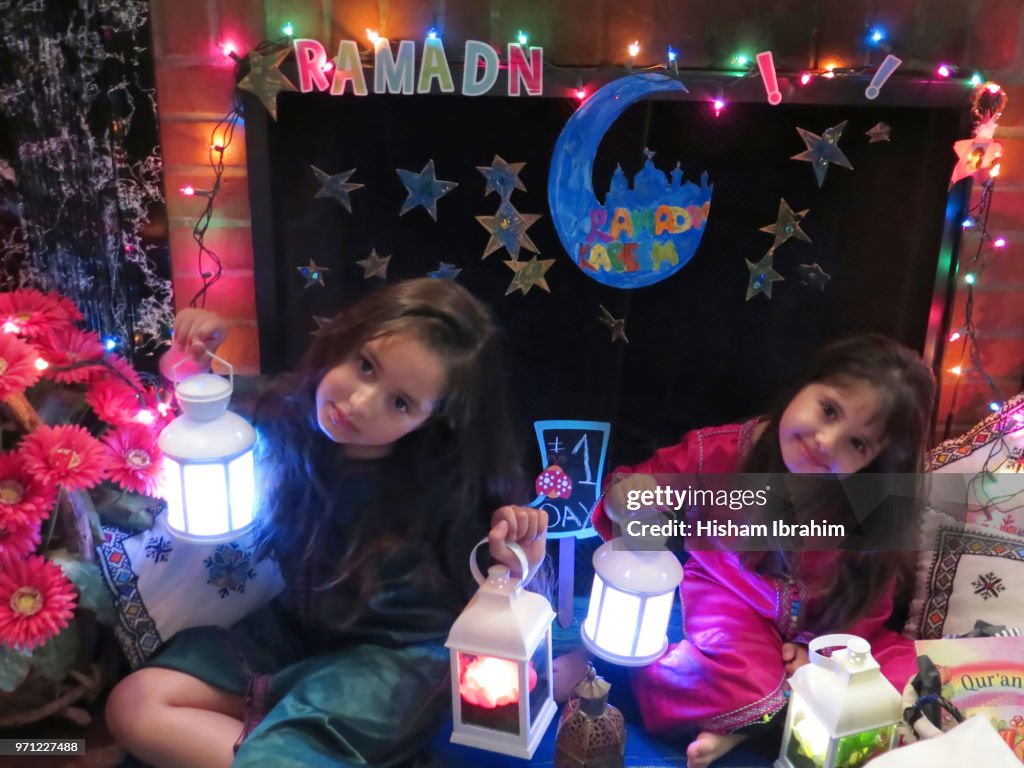 Two sisters 3 years and 6 years old celebrating Ramadan, holding Ramadan lanterns.