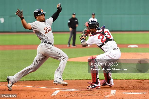 Jeimer Candelario of the Detroit Tigers is safe at home plate as he avoids the tag of Blake Swihart of the Boston Red Sox in the first inning of a...