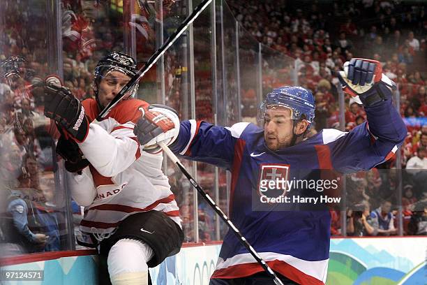 Dany Heatley of Canada is checked to the boards by Andrej Meszaros of Slovakia during the ice hockey men's semifinal game between the Canada and...