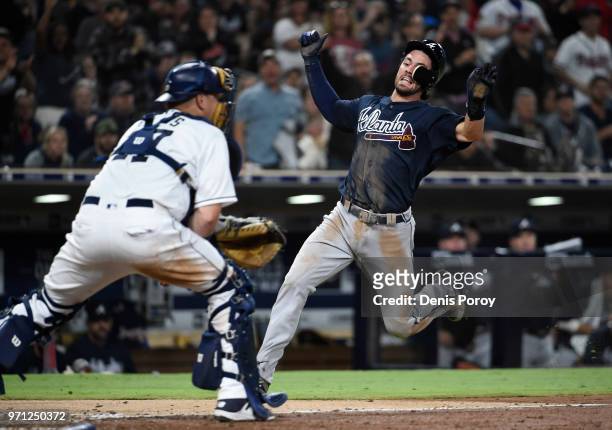 Dansby Swanson of the Atlanta Braves scores ahead of the tag of A.J. Ellis of the San Diego Padres during the seventh inning of a baseball game at...