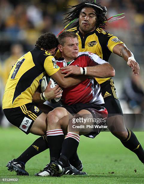 Deon van Rensburg of the Lions is tackled by Aaron Cruden and Ma'a Nonu of the Hurricanes during the round three Super 14 match between the...