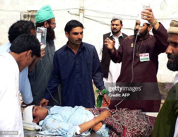 Pakistani relatives stand next to an injured youth at a hospital in Dera Ismail Khan on February 27 after gunmen opened fire on a religious...