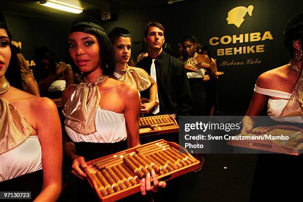 Cuban models carry Cuban Cohiba cigars at an auction of humidors and gala dinner smoke Cuban cigars at the end of the annual five day Habanos Tobacco...