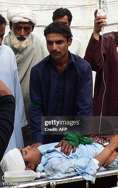 Pakistani relatives stand next to an injured youth at a hospital in Dera Ismail Khan on February 27 after gunmen opened fire on a religious...