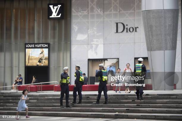 Police stand guard outside a Louis Vuitton store, operated by LVMH Moet Hennessy Louis Vuitton SE, left, and a Christian Dior SE store, in the Ion...