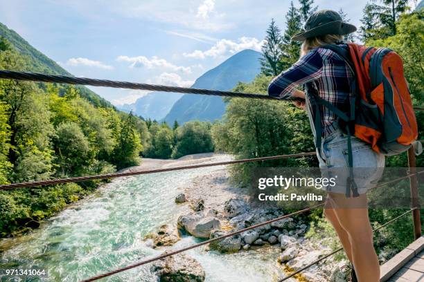 a young woman stands and looks at a hanging bridge, river soca, primorska, slovenia, europe - slovenia hiking stock pictures, royalty-free photos & images