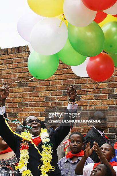 Zimbabwean President Rorbet Mugabe holds balloons next to his son Chatunga on February 27, 2010 during celebrations to mark his 86th birthday in...