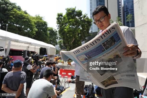 Member of media reads the Straits Times newspaper outside the St. Regis hotel, where North Korean leader Kim Jong Un is staying in Singapore, on...
