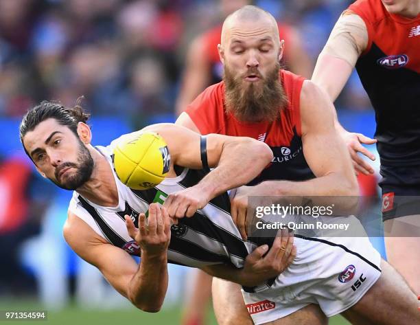 Brodie Grundy of the Magpies handballs whilst being tackled by Max Gawn of the Demons during the round 12 AFL match between the Melbourne Demons and...