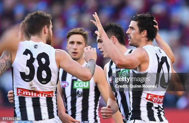 Scott Pendlebury of the Magpies is congratulated by team mates after kicking a goal during the round 12 AFL match between the Melbourne Demons and...