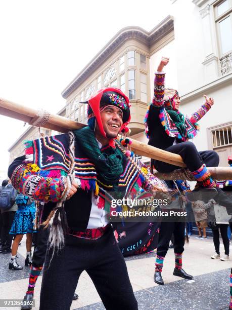 An indigenous man in traditional dress carrying another one in a litter during the grand parade, in the downtown of Lima, for the 69th anniversary of...