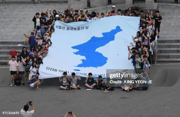 South Korean students unfurl a big reunification flag inscribed with a slogan that reads "We will make a peaceful Korean peninsula with our own...