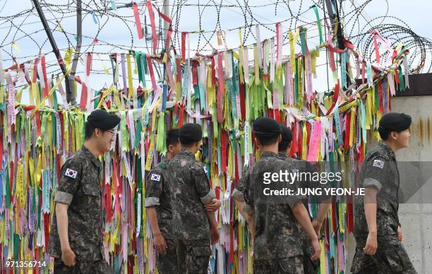South Korean soldiers look at ribbons with inscriptions calling for peace and reunification displayed on a military fence at Imjingak peace park near...