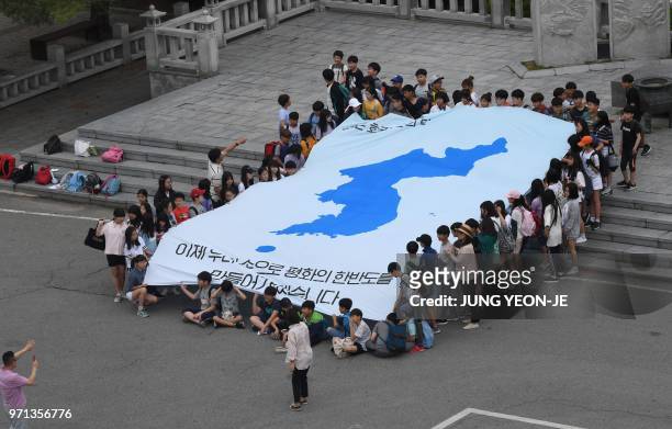 South Korean students unfurl a big reunification flag inscribed with a slogan that reads "We will make a peaceful Korean peninsula with our own...