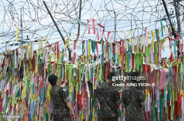 South Korean soldiers look at ribbons with inscriptions calling for peace and reunification displayed on a military fence at the Imjingak peace park...