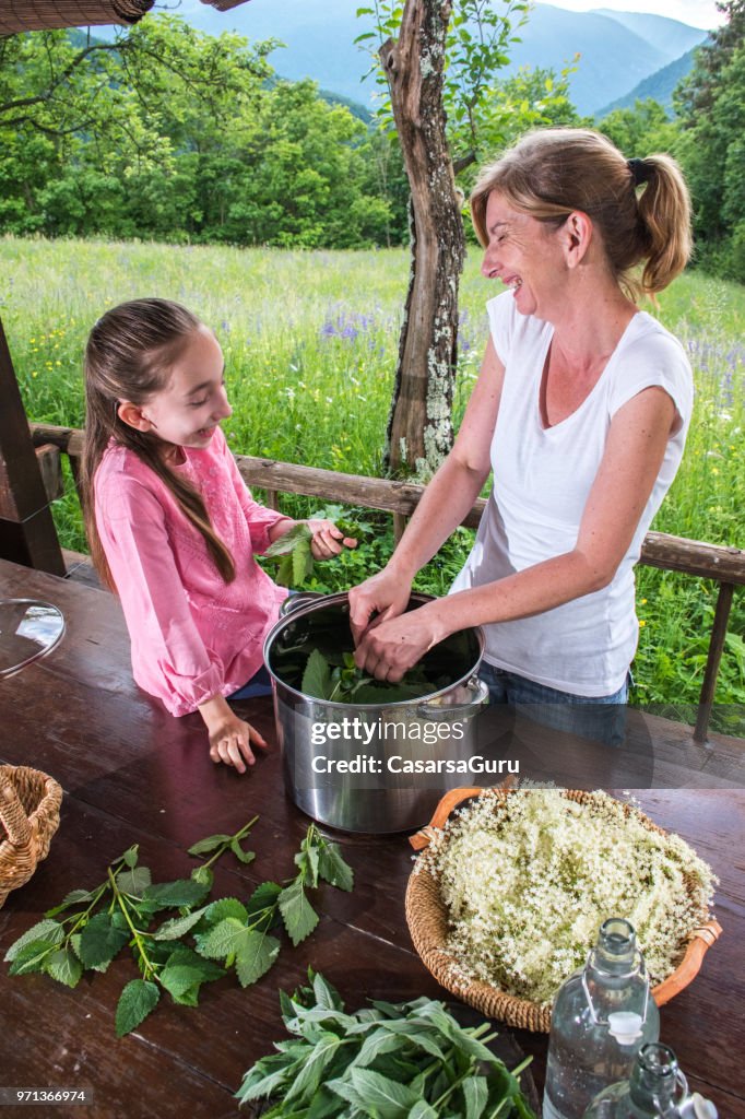 Daughter Helping Mother Preparing Elderflower And Mint Syrup