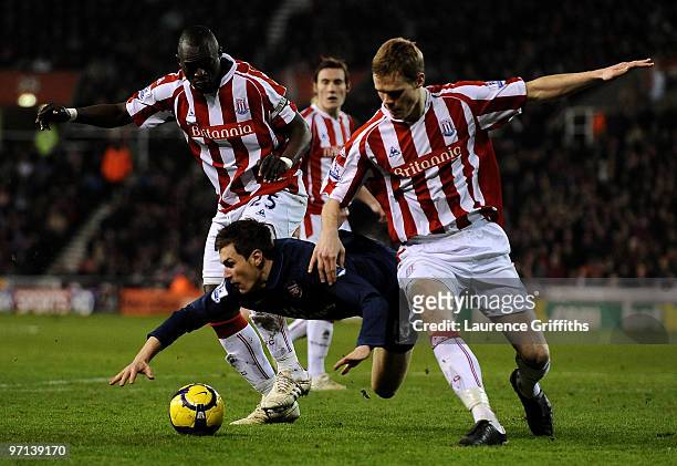Aaron Ramsey of Arsenal is challenged by Abdoulaye Faye and Ryan Shawcross of Stoke City during the Barclays Premier League match between Stoke City...