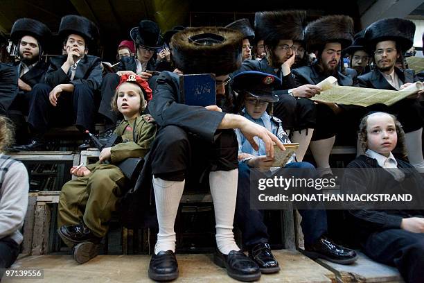 Ultra-Orthodox Jews belonging to the Vishnitz Hassidic sect read the Esther scrolls with children dressed in carnival costume at a synagogue in the...