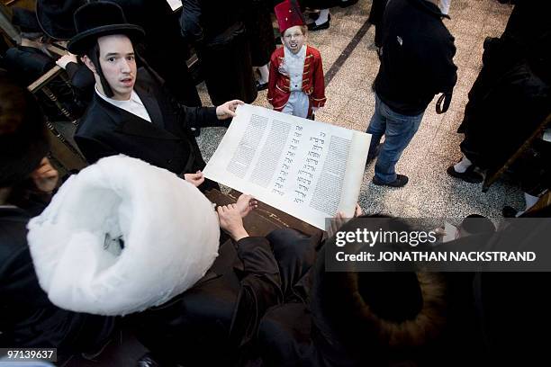 Ultra-Orthodox Jews belonging to the Vishnitz Hassidic sect read the Esther scrolls with children dressed in carnival costume at a synagogue in the...