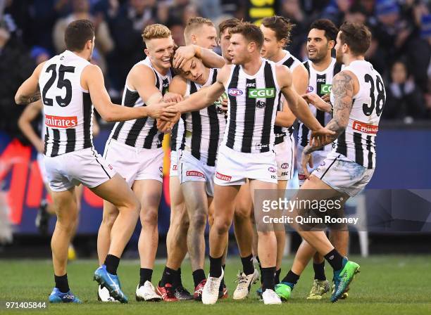 Josh Thomas of the Magpies is congratulated by team mates after kicking a goal during the round 12 AFL match between the Melbourne Demons and the...