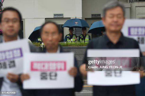 Policemen stand guard in front of the US embassy while anti-war activists hold a rally wishing for a successful summit between US President Donald...