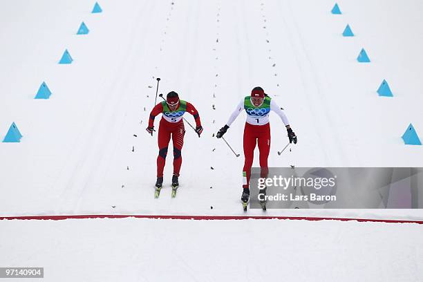 Justyna Kowalczyk of Poland crosses the finish line in first place ahead of Marit Bjoergen of Norway during the ladies' 30 km mass start...