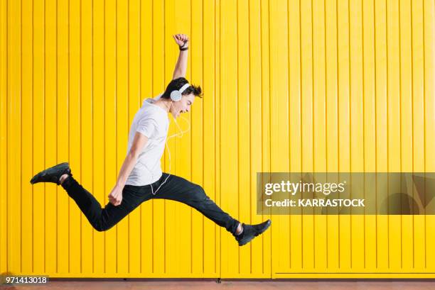 teen with headphones and smartphon listening to music jumping - man jump outdoor young city stock pictures, royalty-free photos & images