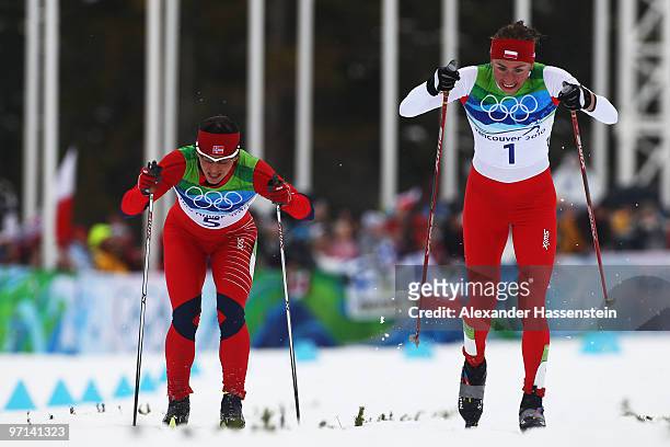 Justyna Kowalczyk of Poland leads Marit Bjoergen of Norway to the finish line during the ladies' 30 km mass start cross-country skiing classic on day...