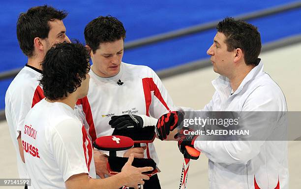 Switzerland's skip Markus Eggler discusses with teammates Ralph stoeckli , Jan Hauser and Simon Struebin during the men's 2010 Winter Olympics bronze...