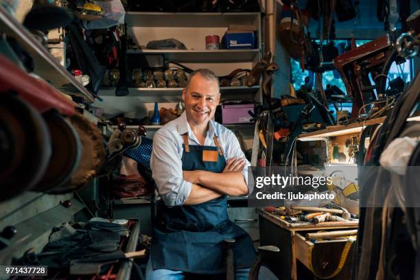 portrait of shoemaker sitting with arms crossed in workshop - leather industry stock pictures, royalty-free photos & images