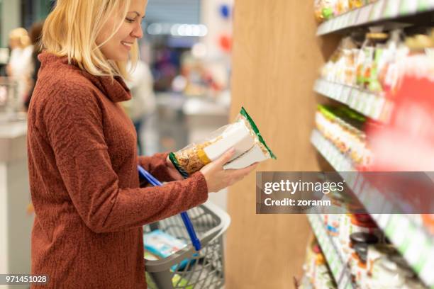 woman buying wholegrain fusilli - wholegrain pasta stock pictures, royalty-free photos & images