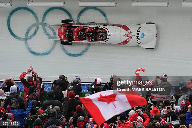 Members of the Canada-1 team piloted by Lyndon Rush slide past the Olympic Rings on their final run before winning Bronze in the Men's Four-Man...