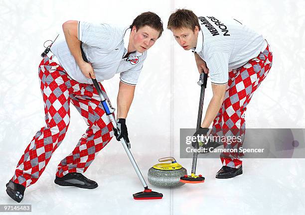 Torger Nergaard and Christoffer Svae of Norway sweep the ice in front of a stone during the Curling Men's Gold medal game between Canada and Norway...