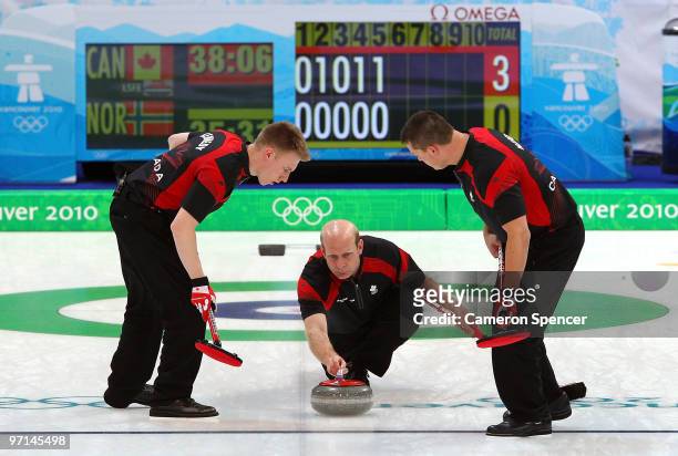 Marc Kennedy and John Morris of Canada prepare to sweep the ice ahead of the stone thrown by Kevin Martin during the Curling Men's Gold medal game...