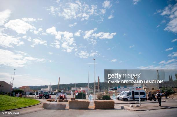 Riot policemen stand near straw bales blocking the access of French oil giant Total's La Mede refinery in Chateauneuf-les-Martigues, southern France,...