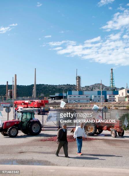 Men walk near tractors blocking the access of French oil giant Total's La Mede refinery in Chateauneuf-les-Martigues, southern France, on June 11,...