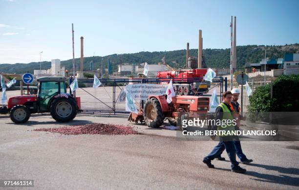 Workers walk near tractors blocking the access of French oil giant Total's La Mede refinery in Chateauneuf-les-Martigues, southern France, on June...
