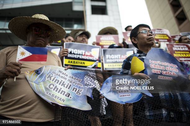 Activists hold placards during a protest in front of the Chinese Consular Office in Manila on June 11, 2018. - The Philippines on June 11 demanded...