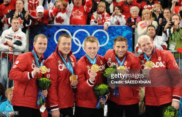 Canada's curling team Canada's Kevin Martin, John Morris, Marc Kennedy, Ben Hebert and Adam Enright display their gold medal on the podium during the...