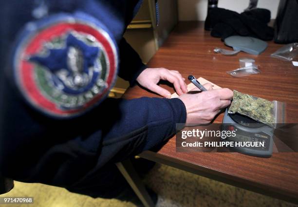 Lille's French customs officer weighs sealed marihuana he seized on February 3, 2011 at the Rekkem Franco-Belgian border checkpoint in...