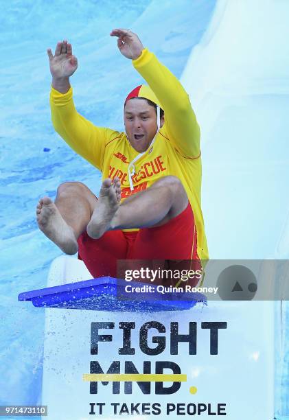 Suns head coach Stuart Dew goes down the Freeze MND slide during the round 12 AFL match between the Melbourne Demons and the Collingwood Magpies at...