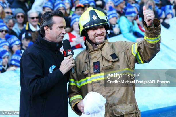 Magpies head coach Nathan Buckley gestures after going down the MND slide during the round 12 AFL match between the Melbourne Demons and the...