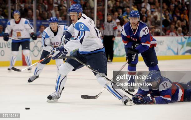 Olli Jokinen of Finland is challenged by Lubomir Visnovsky of Slovakia during the ice hockey men's bronze medal game between Finland and Slovakia on...