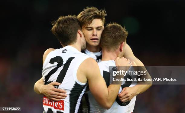 Josh Thomas of the Magpies is congratulated by his teammates after kicking a goal during the round 12 AFL match between the Melbourne Demons and the...
