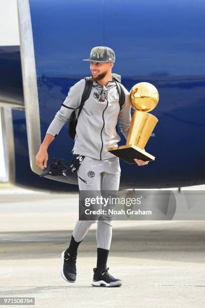 Stephen Curry of the Golden State Warriors exits the plane with the Larry O'Brien Championship Trophy as he arrives at Oakland International Airport...