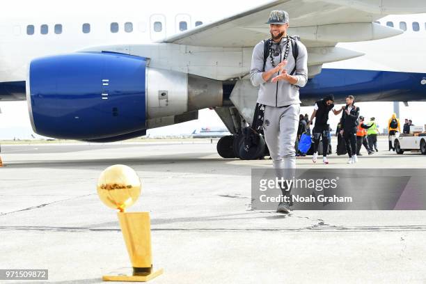 Stephen Curry of the Golden State Warriors exits the plane with the Larry O'Brien Championship Trophy as he arrives at Oakland International Airport...